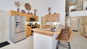 Een moderne keuken met houten kasten, roestvrijstalen apparatuur en een centraal kookeiland met barstoelen.