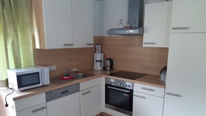 A compact kitchen with a microwave, coffee maker, oven, and dishwasher.