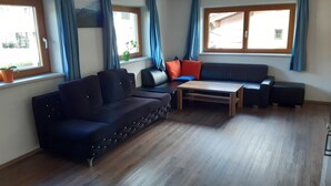 A modern living room with a dark sofa, a wooden coffee table, and a window with blue curtains.