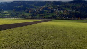 A rural landscape with fields, a plowed area, and a village in the background. - Apartment "Gertis Top 2" with Mountain View, Wi-Fi & Balcony (Stumm)