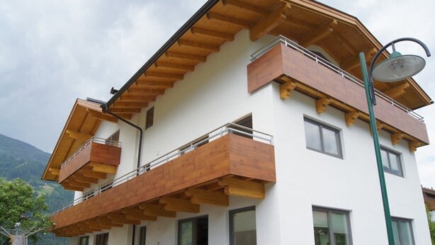 A multi-story building with wooden balconies, a satellite dish, and a street lamp. - Apartment "Gertis Top 2" with Mountain View, Wi-Fi & Balcony (Stumm)