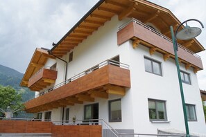 Un edificio de varios pisos con balcones de madera, una antena parabólica y una farola.