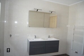 Un baño con dos lavamanos, un espejo y un perchero para toallas.
