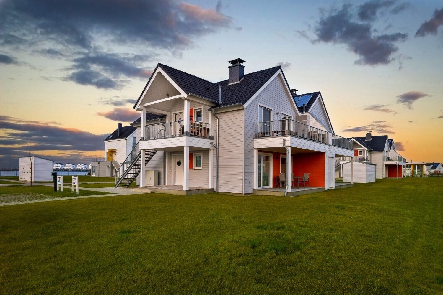 Ein modernes, zweistöckiges Haus mit Balkon, einer überdachten Veranda und Blick auf das Meer.