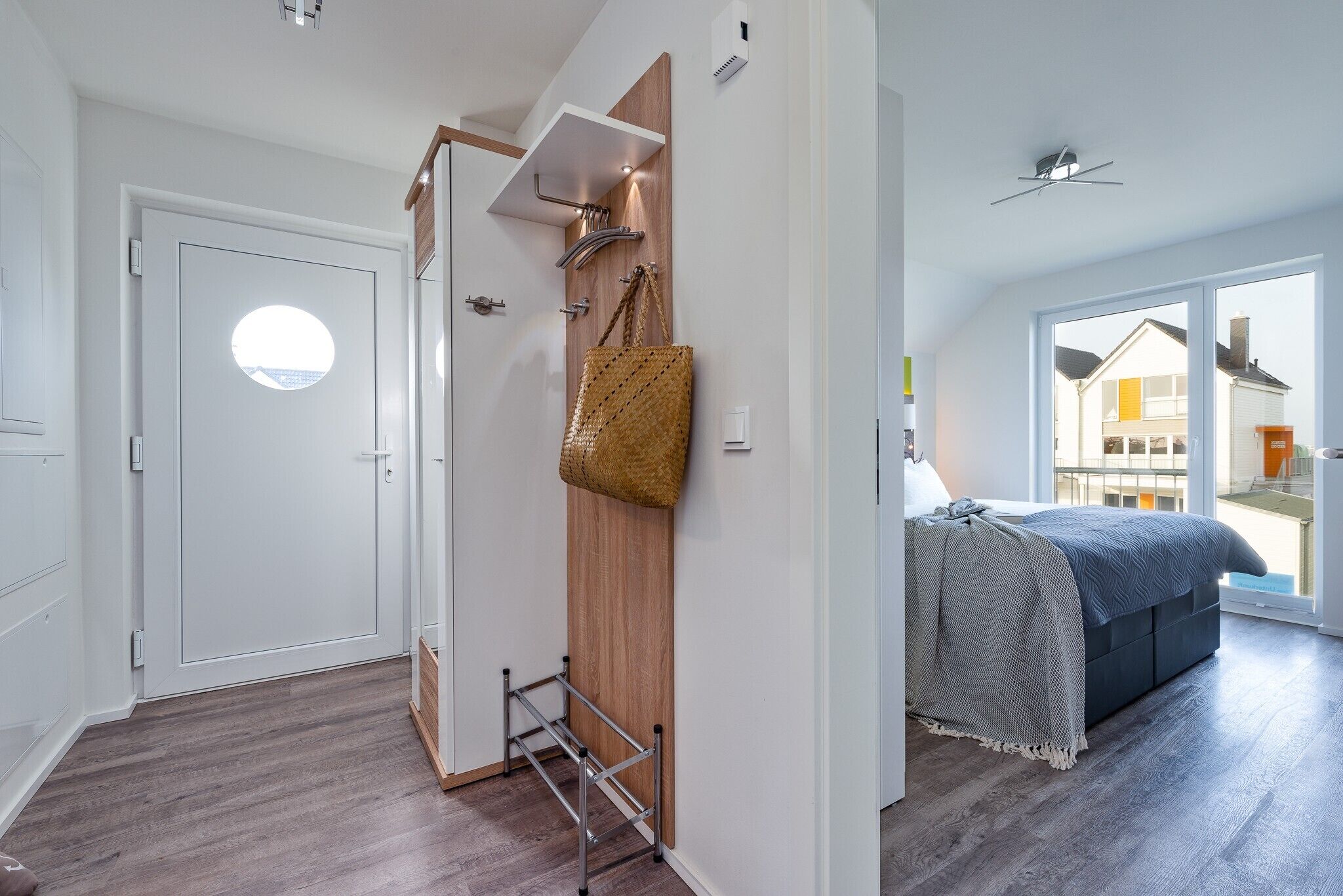 A modern bedroom with a bed, a wooden wardrobe, a hanging basket, and a window with a view.
