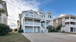 A multi-story residential building with a central staircase, a garage, and a covered front porch. - 5566- Pearl Jam - Nags Head Retreat w/ Pool, Hot Tub & Theater (Nags Head)