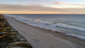 A beach with a long stretch of sand and a few buildings in the distance. - 5566- Pearl Jam - Nags Head Retreat w/ Pool, Hot Tub & Theater (Nags Head)