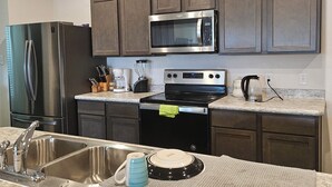 A kitchen with stainless steel appliances, dark wooden cabinets, and a granite countertop.