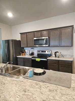 A kitchen with stainless steel appliances, dark wooden cabinets, and a granite countertop.