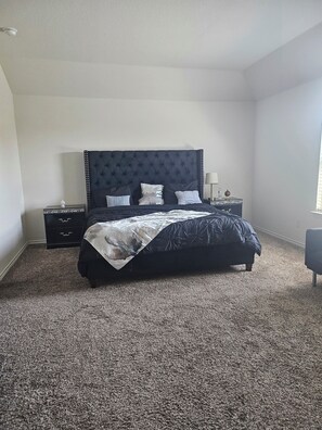 Une chambre à coucher avec un grand lit, deux tables de chevet, une commode et une fenêtre.