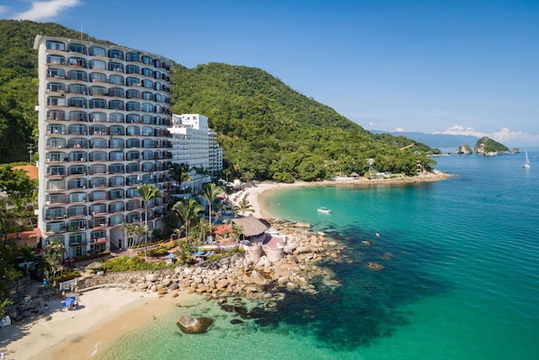 A multi-story hotel with balconies, a beach, and clear turquoise waters. - Beachfront 2 Bedroom Flat with Panoramic Ocean Views (Puerto Vallarta)