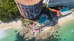 Eine Vogelperspektive zeigt ein Resort mit einem kreisförmigen Gebäude, einem Strand und einem Pool.