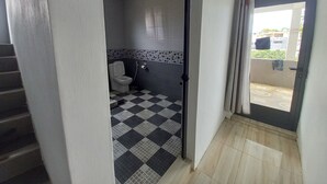 Une salle de bain avec un carrelage à motifs géométriques, des toilettes et une douche.