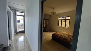 Une chambre spacieuse avec un grand lit, un ventilateur de plafond et une fenêtre donnant sur l’extérieur.