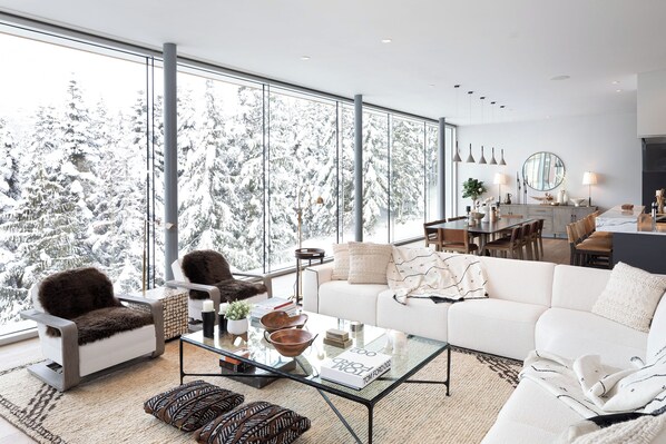 A modern living room with a large window, a glass coffee table, and a sofa.