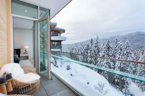 A modern balcony with a glass railing overlooking a snowy mountain landscape. - Kadenwood 2980 - Ski in Ski out, Private Pool, Hot Tub & Gondola (Whistler)