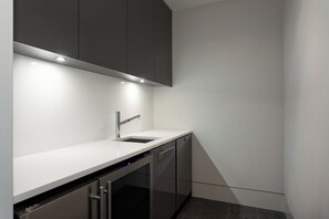 A modern kitchen with a white countertop, stainless steel appliances, and dark cabinetry.