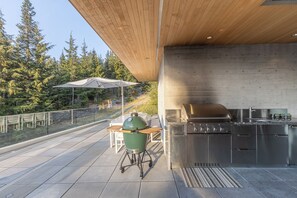 An outdoor patio with a grill, a table, and chairs.