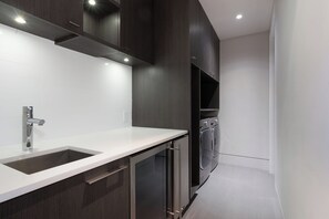 A modern kitchen with dark wood cabinets, a white countertop, stainless steel appliances, and recessed lighting.