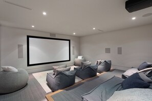 A modern home theater room with a large flat-screen TV, comfortable seating, and a minimalist design.