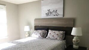 Un dormitorio con una cama, dos mesitas de noche, una lámpara de pared y un cuadro con leones.