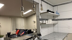 Una cocina moderna con encimera de granito, pileta de acero inoxidable y lámparas colgantes.
