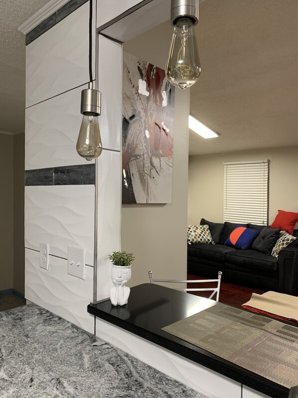 A modern kitchen with a marble countertop, pendant lights, and a white backsplash.