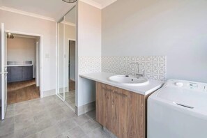 Ein Badezimmer mit einem Holzbadschränken, einem weißen Waschbecken und einer Waschmaschine.