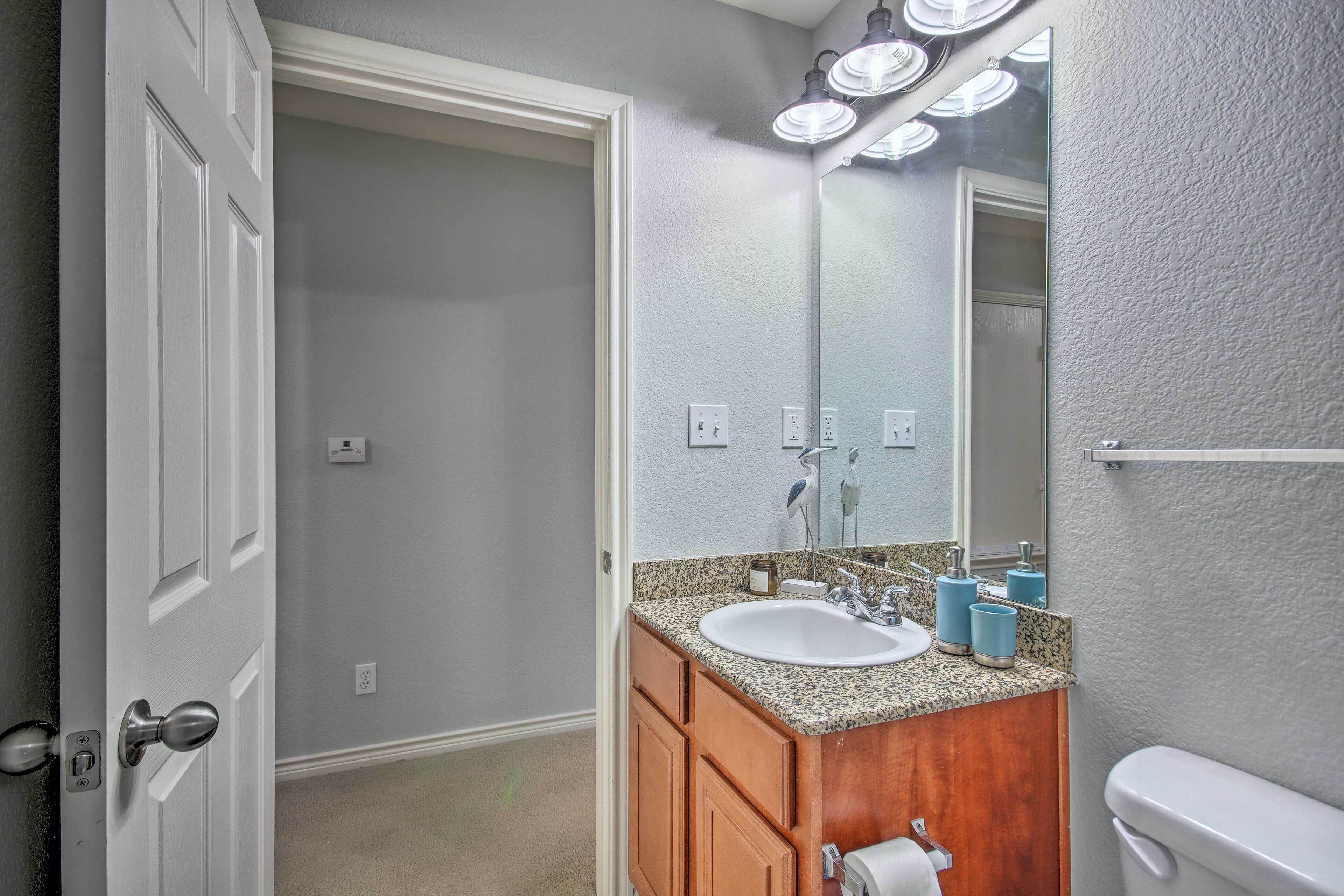 Une salle de bain avec un lavabo blanc, un meuble-lavabo en bois et un miroir au-dessus.