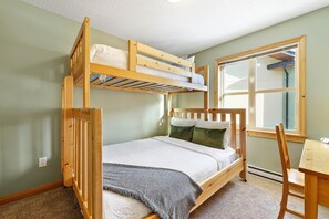 A bunk bed room with a window, a desk, and a chair.