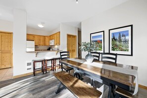 A modern kitchen with wooden cabinets, a built-in microwave, and a dining area with a wooden table and benches.