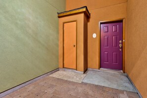 A hallway with two doors, one orange and one purple, and a number '50' sign on the wall.
