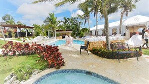 A pool area with lounge chairs, a hot tub, and a covered seating area with tables.