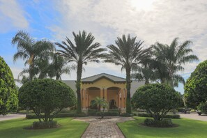 A building with a central entrance, surrounded by palm trees and well-maintained lawns.