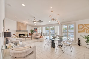 Relax in the open-plan living area with a central dining table, sofas, and armchairs, offering a view of the outdoor patio.