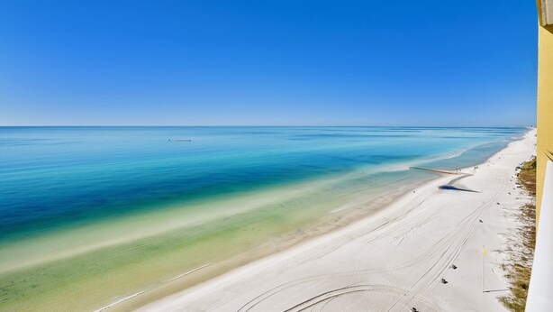 A beach with clear blue water and a sandy shore.