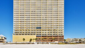 A high-rise hotel with multiple floors and balconies, located near a beach.