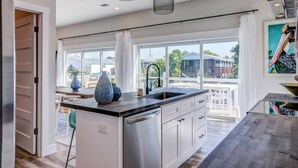 A modern kitchen with a large island, white cabinetry, and pendant lighting. - The Salty Sailfish: Live the Keys Life, Stunning Canal Front Home, Pool, Dock & Dog-Friendly Bliss! (Summerland Key)