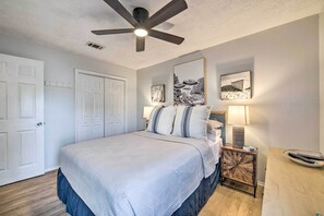 A bedroom with a bed, ceiling fan, two wall-mounted lamps, and a side table with a remote control. - PCB Condo Rental w/ Pool Access, Steps to Beach! (Panama City Beach)