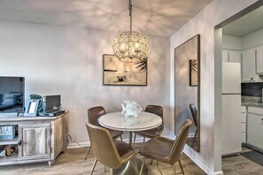 A dining area with a round table, four chairs, a hanging light fixture, and artwork on the walls. - PCB Condo Rental w/ Pool Access, Steps to Beach! (Panama City Beach)