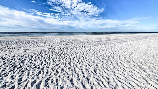A wide sandy beach with footprints, a clear sky, and the ocean in the background. - PCB Condo Rental w/ Pool Access, Steps to Beach! (Panama City Beach)