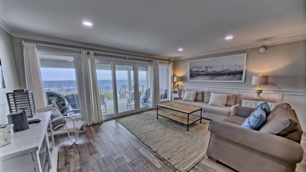 A spacious living room with a large window, a sofa, a coffee table, and a view of the outdoors.