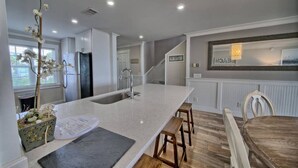 A modern kitchen with a large island, built-in appliances, and a dining area with wooden chairs.