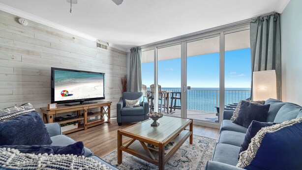 Ein modernes Wohnzimmer mit Fernseher, Sofa, Couchtisch und Meerblick durch große Fenster.