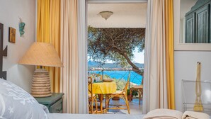 A bedroom with a bed, a bedside table with a lamp, a window with curtains, and a view of the sea. - Apartment 'Bella Vista Marinella 1' with sea view, terrace, air conditioning and Wi-Fi (Olbia)