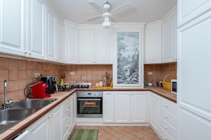A kitchen with white cabinets, a built-in oven, a coffee maker, and a painting on the wall.