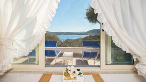 Una habitación con vista al mar, una mesa con un arreglo floral y una ventana con cortinas blancas.