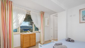 Un dormitorio con cama, cómoda, ventana con cortinas y vistas al exterior.
