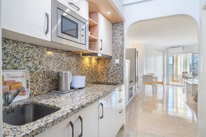 Uma cozinha moderna com bancadas de granito, eletrodomésticos de aço inoxidável e vista para a sala de jantar.