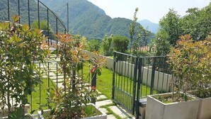 Un jardin avec une clôture en métal, des plantes en pot et une vue sur les montagnes.